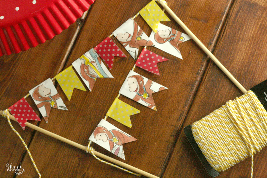 Learn how to make an adorable bunting cake topper out of book pages and washi tape from hunnyimhomediy.com | DIY bunting cake topper | bunting cake topper DIY | bunting cake topper baby | book page cake topper | book page crafts | flag cake topper DIY | book cake topper | DIY birthday cake topper | Curious George cake topper