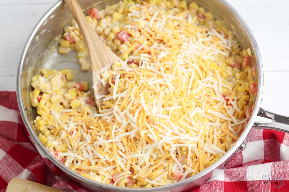 Add shredded cheese to corn casserole