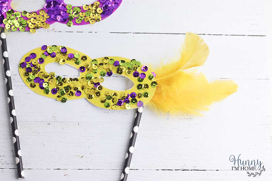 Attach feathers and a straw handle to the printable Mardi Gras masks