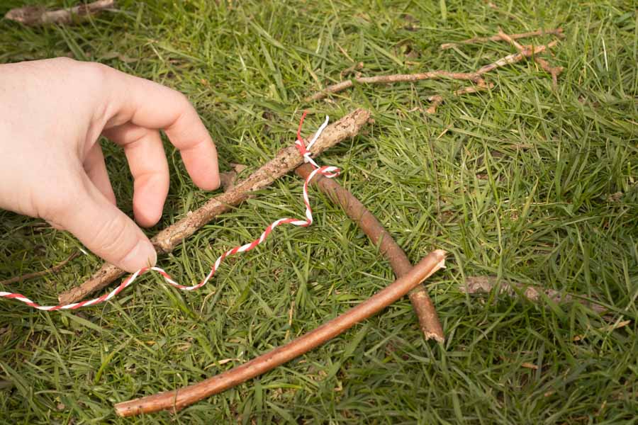 Sticks laid out in a frame with one corner already woven together